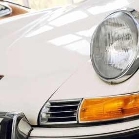 Frontansicht eines weißen Oldtimer Porsche mit klassischem Scheinwerfer und Blinker.